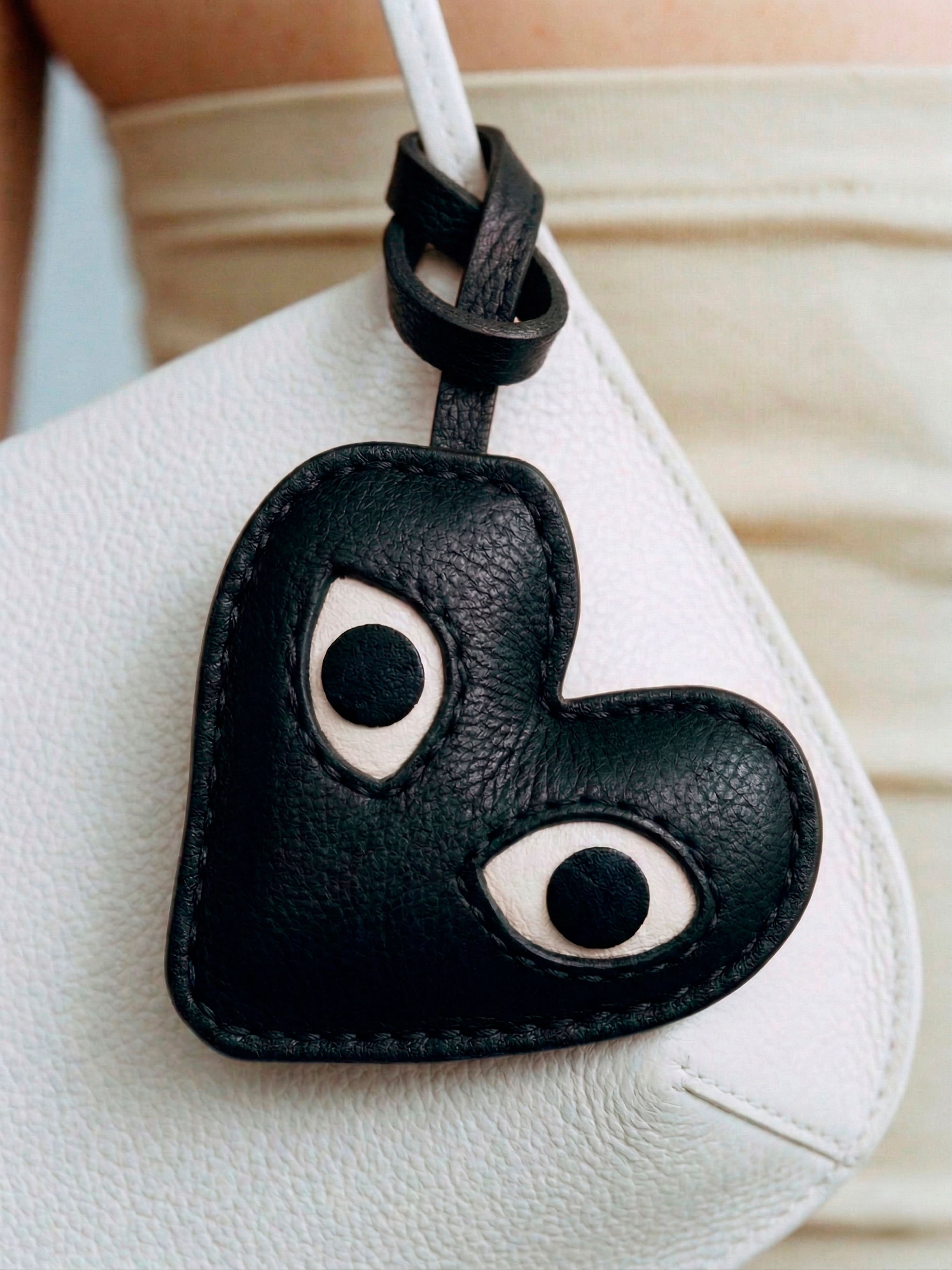 Bag Charm Coração com Olhos preto preso a bolsa em close - Charmme Brasil